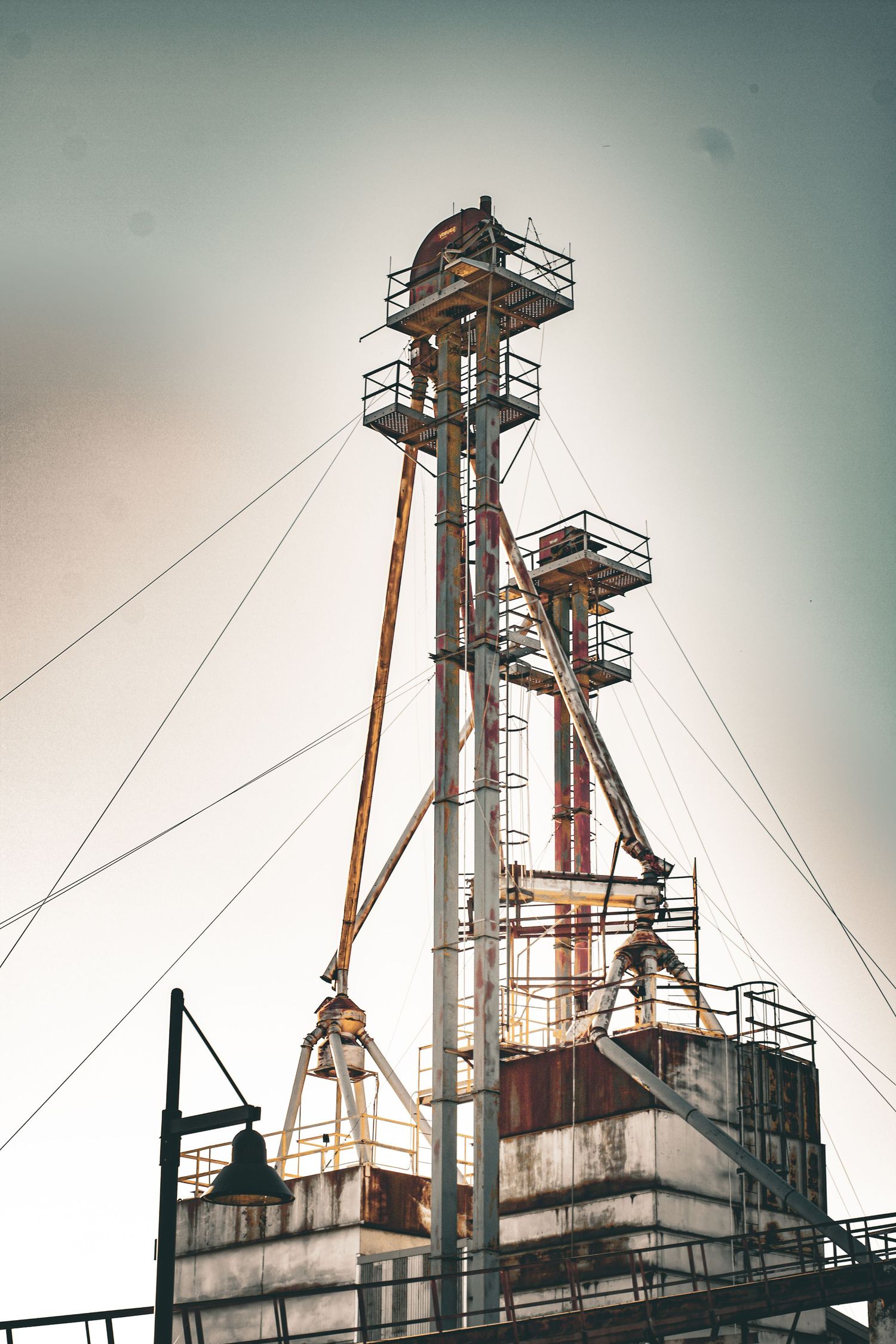 Industrial metal towers and scaffolding silhouetted against a gradient sky at dusk.