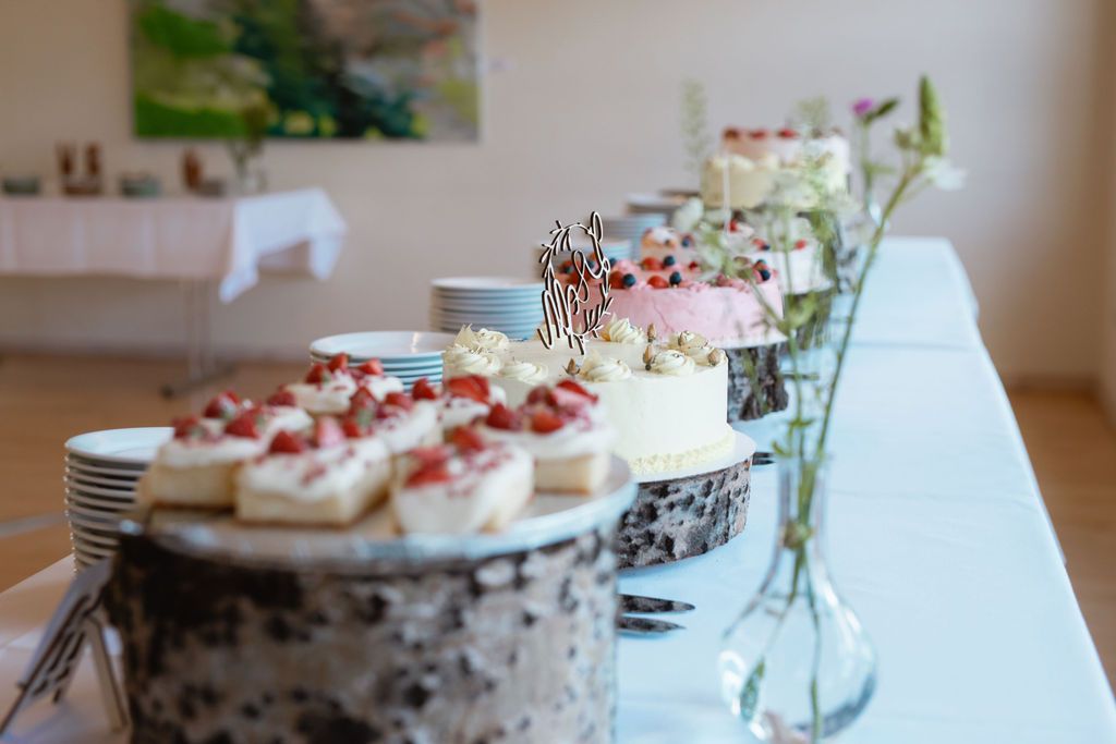 A row of elegant desserts with whipped cream and berries displayed on decorative stands at a wedding reception.