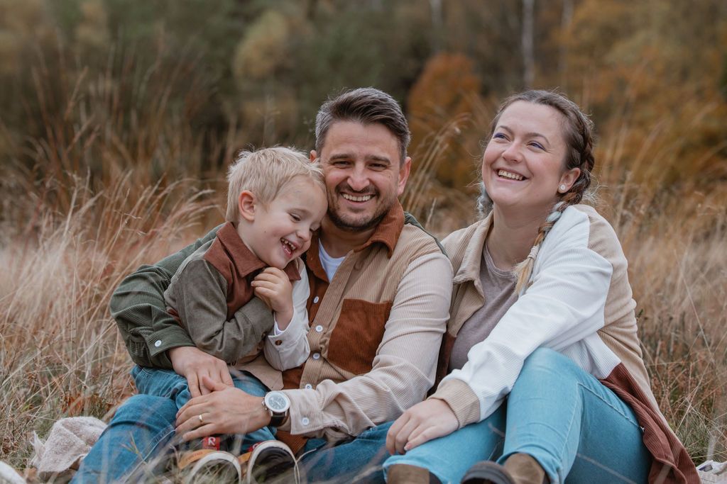 Family members sharing intimate moments during fall photo session in field.