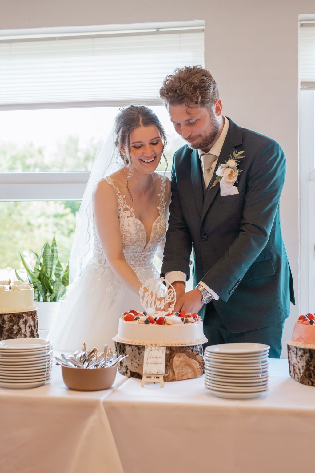 A couple cuts their wedding cake together at an elegant reception table setting.