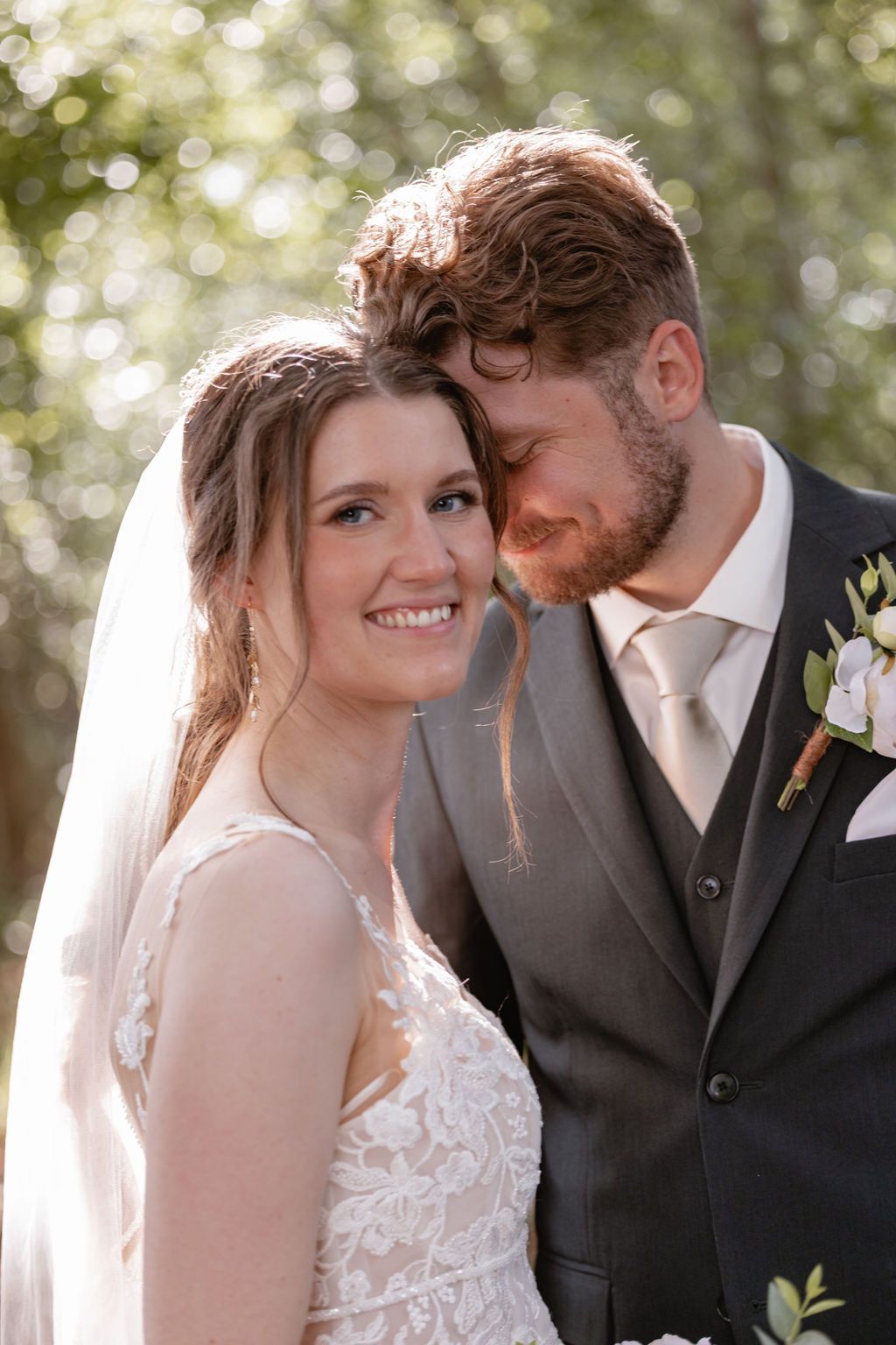 Intimate wedding portrait of couple sharing a tender moment in natural outdoor lighting.