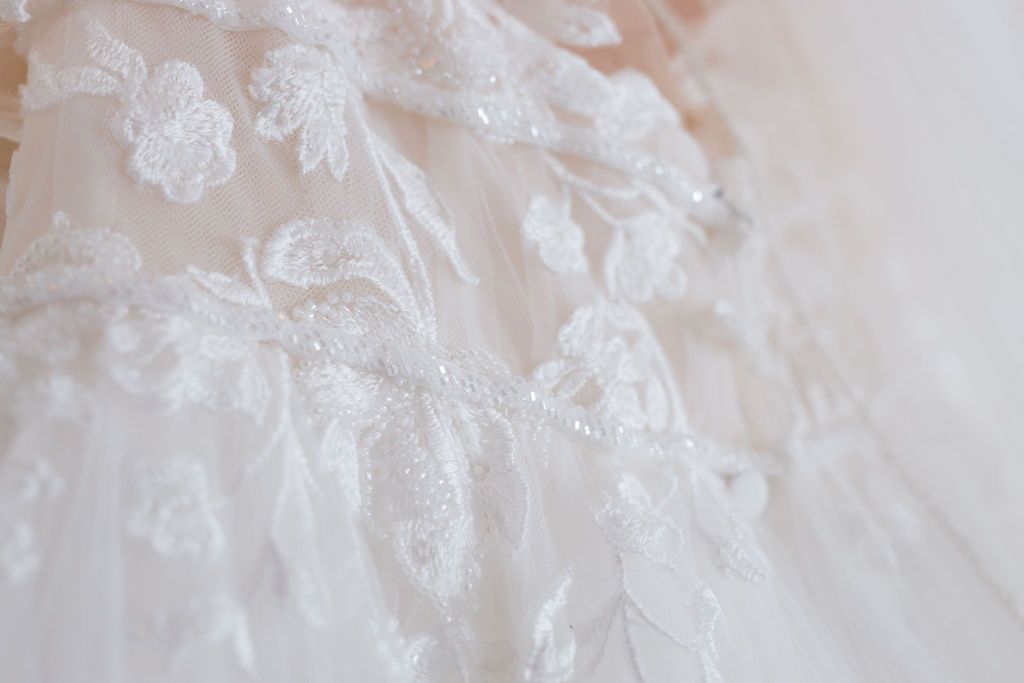 Close-up detail of delicate white lace patterns on a wedding dress fabric.