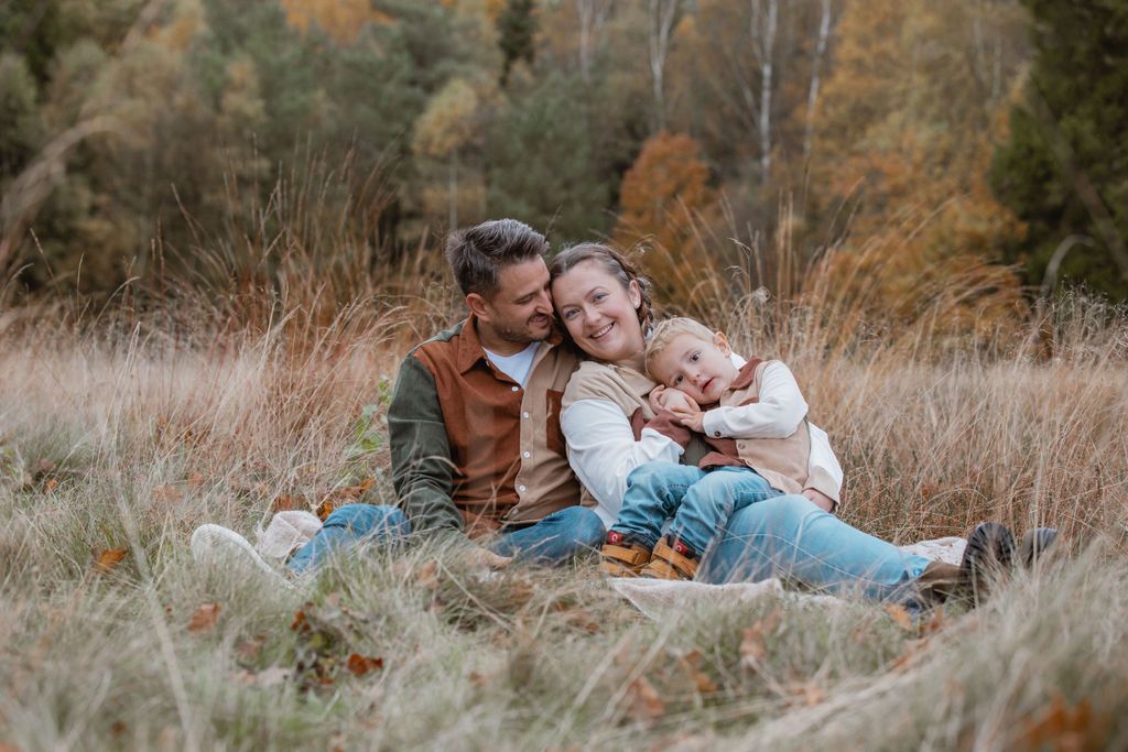 Couple relaxes together in tall grass during autumn afternoon.