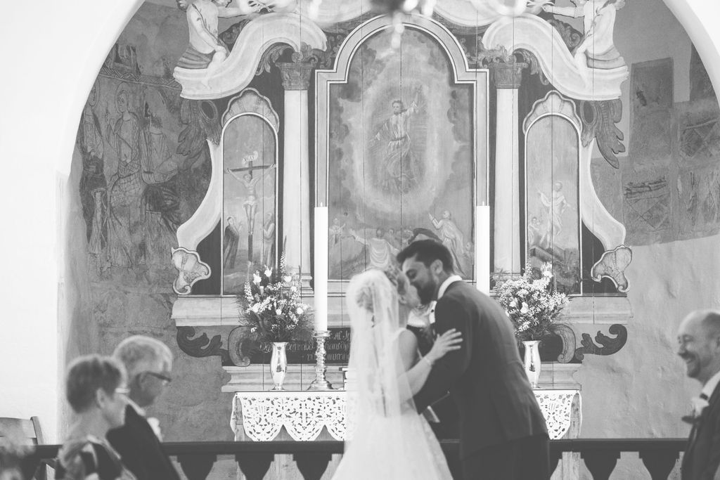 Black and white photo of intimate wedding ceremony moment in historic church setting.