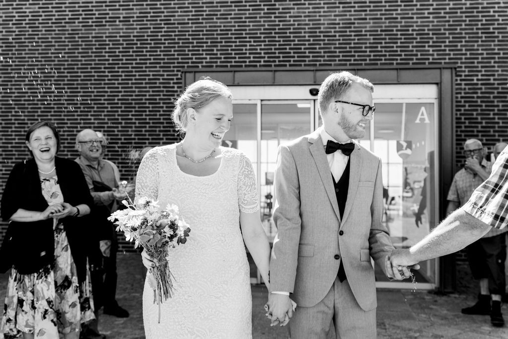 Stemningsfuldt øjeblik efter vielse med gæster i baggrunden, bryllup Jylland