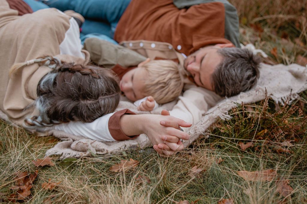 People relaxing on blankets in autumn grass during an outdoor gathering.