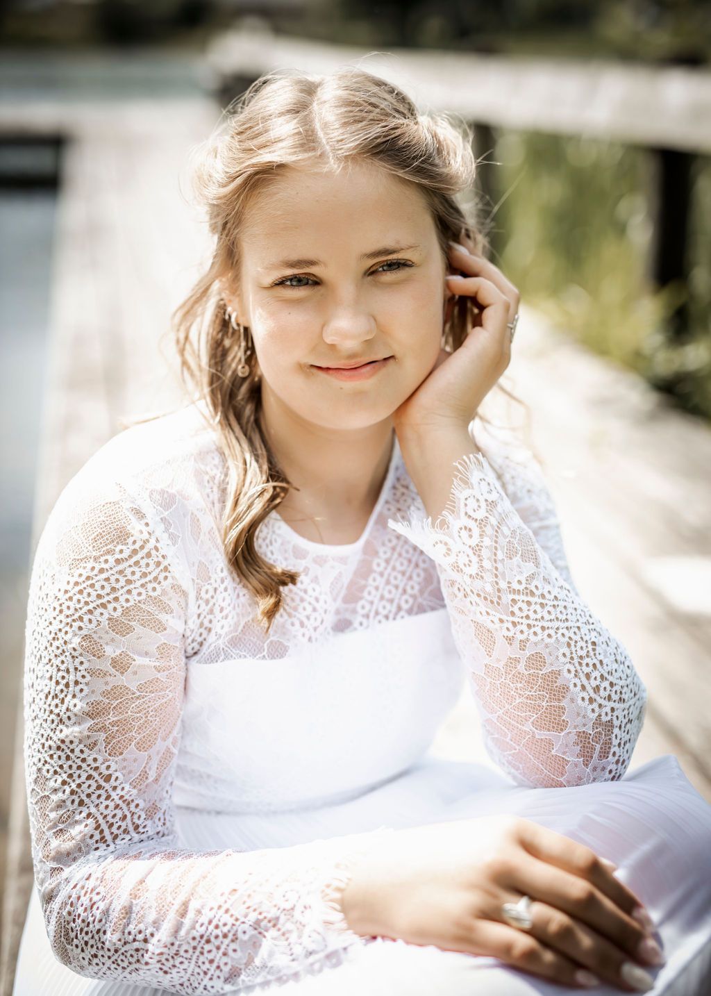 Person in white lace top with sheer sleeves poses during outdoor portrait session.