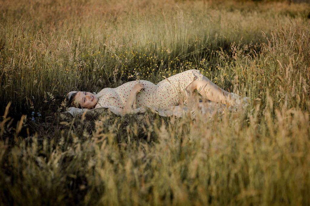Artistic maternity portraits taken in a golden field at sunset.