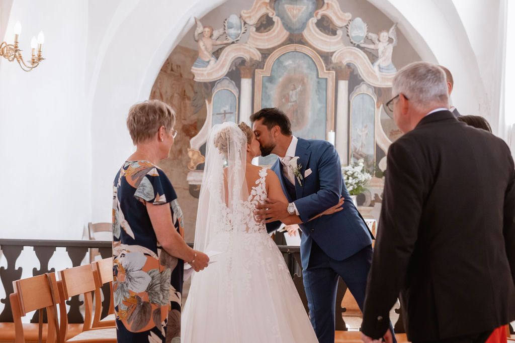 Traditional church ceremony with ornate altar decorations and white floral arrangements.
