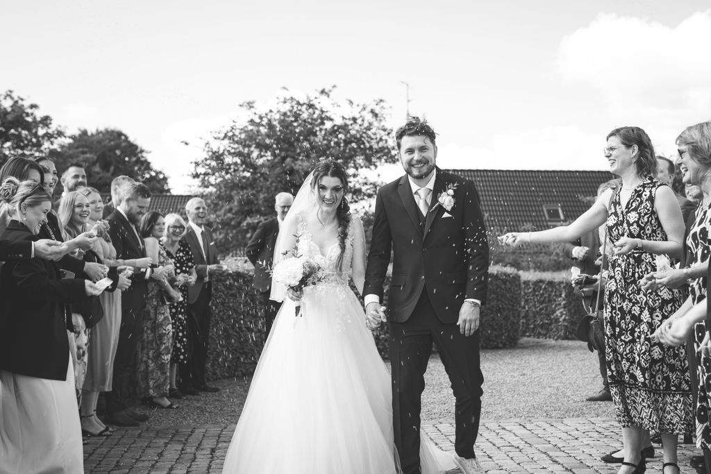 Wedding party celebrates outdoors with guests during a sunny outdoor reception.