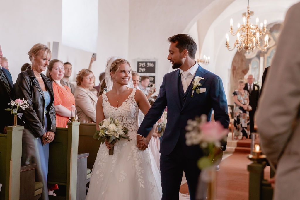 Celebratory moment in church aisle with guests looking on.