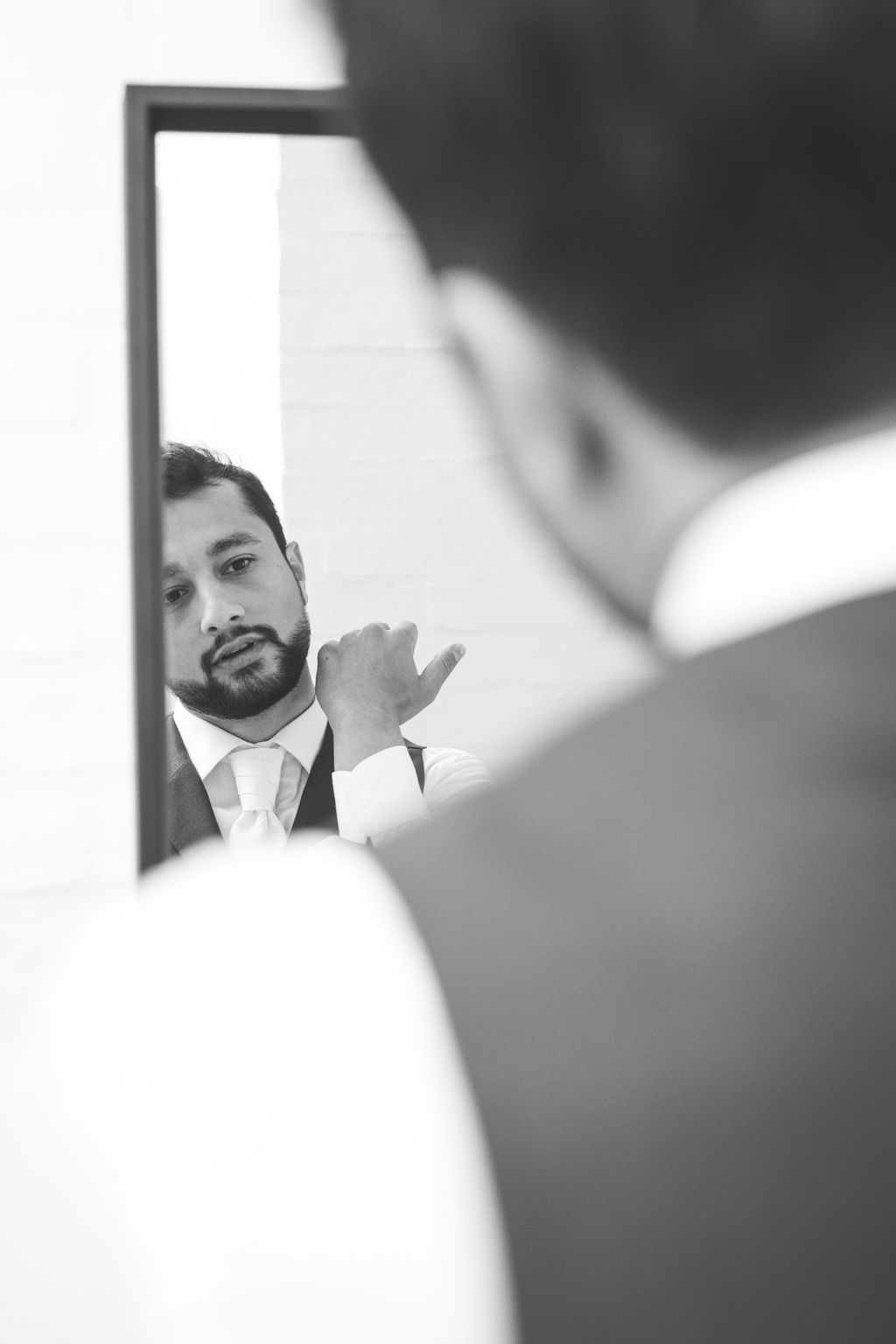 A black and white reflection of wedding day preparations in a mirror.