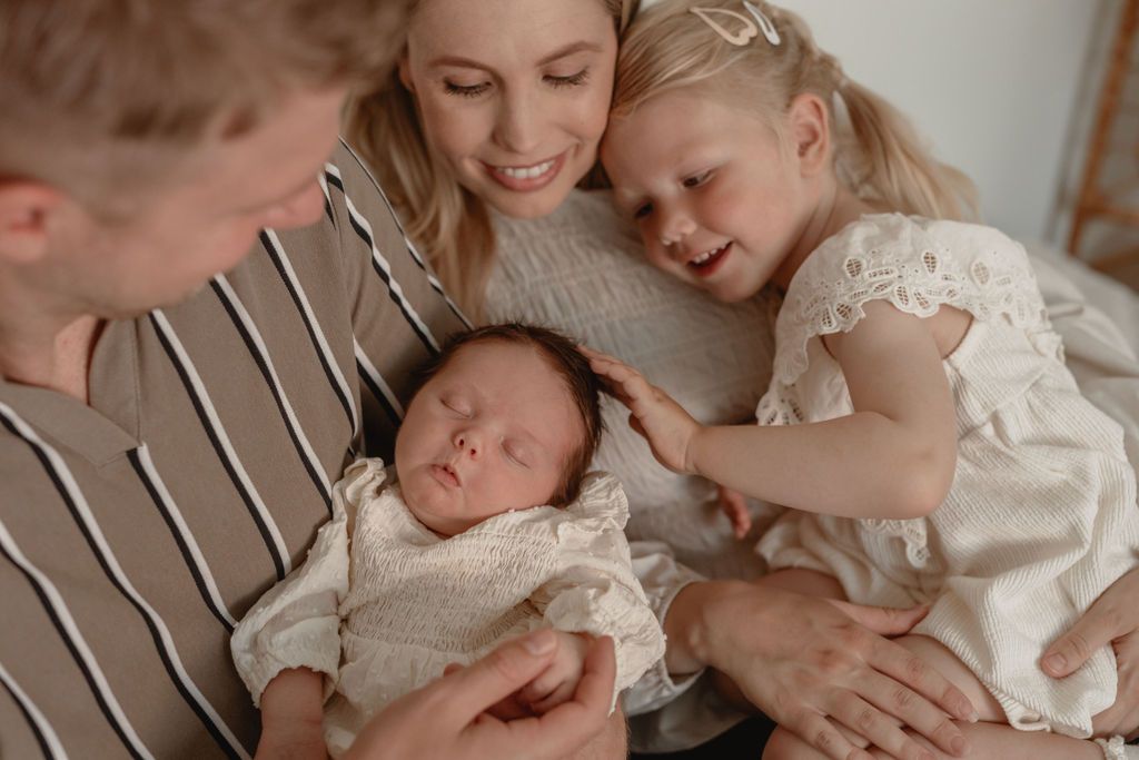 Intimate family moment showing cuddles with a newborn in soft, neutral tones.