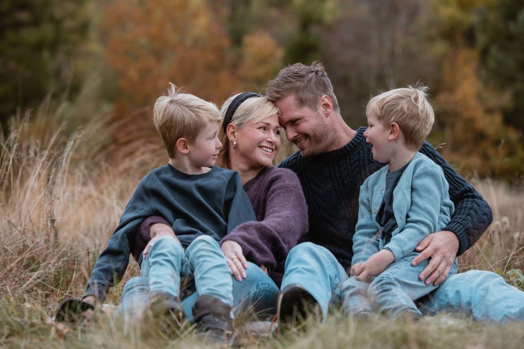 Family shares intimate moment of laughter while sitting in autumn field.