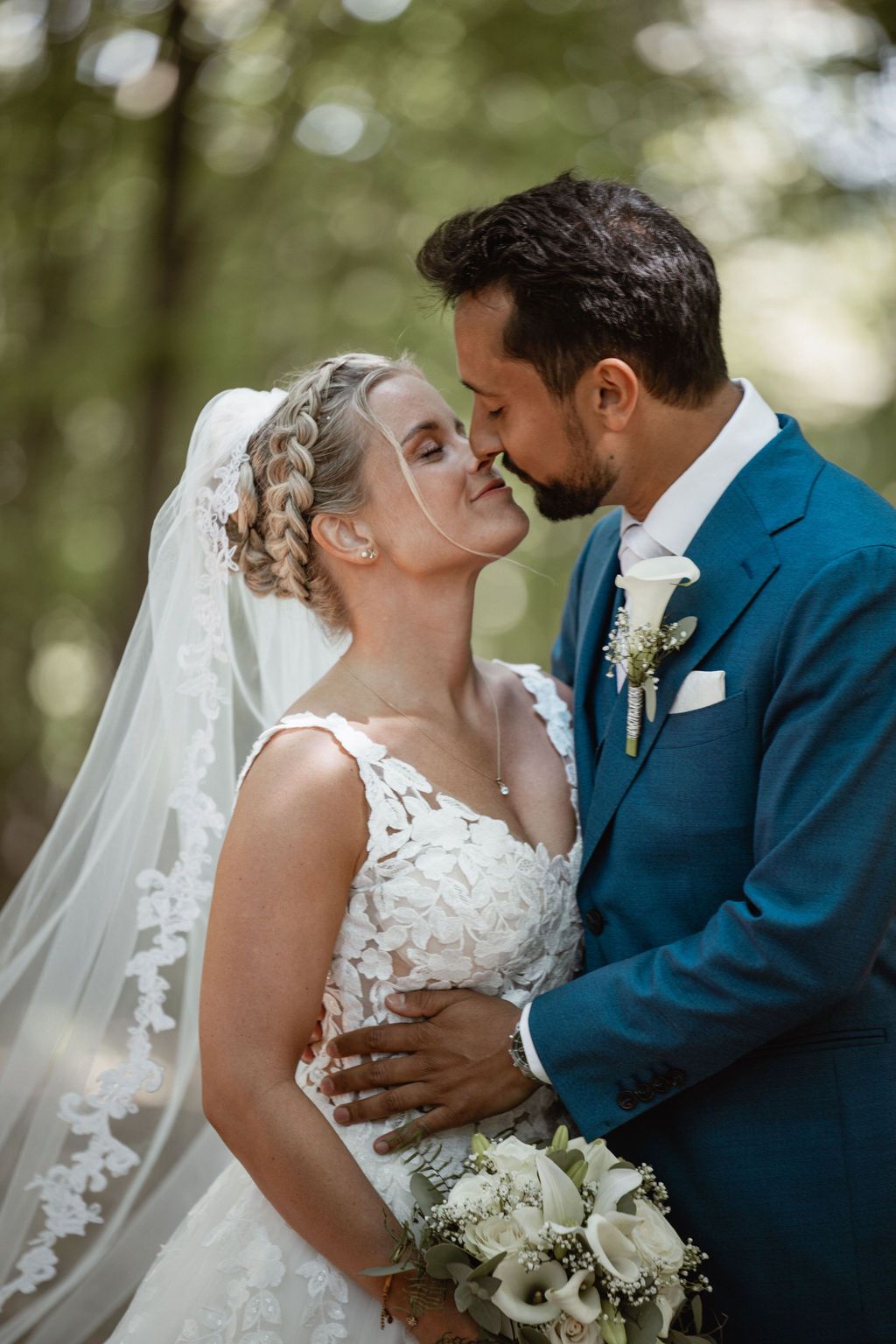 Intimate wedding portrait of couple sharing a romantic moment with white floral bouquet.