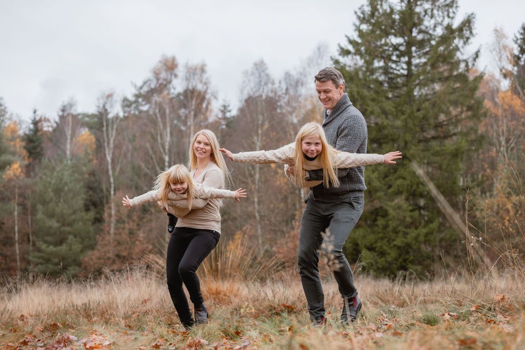 Family plays and has fun together in an autumn forest setting.
