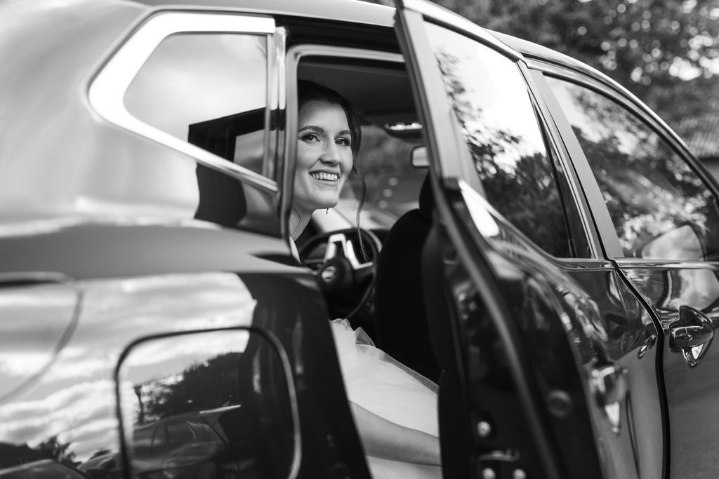 Wedding couple shares joyful moments while sitting in a vintage car after their ceremony.