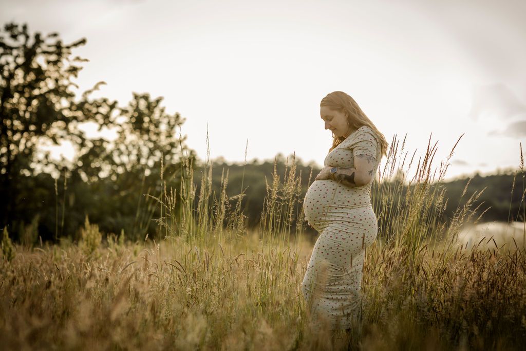 Silhouette maternity photos taken in a field during sunset.