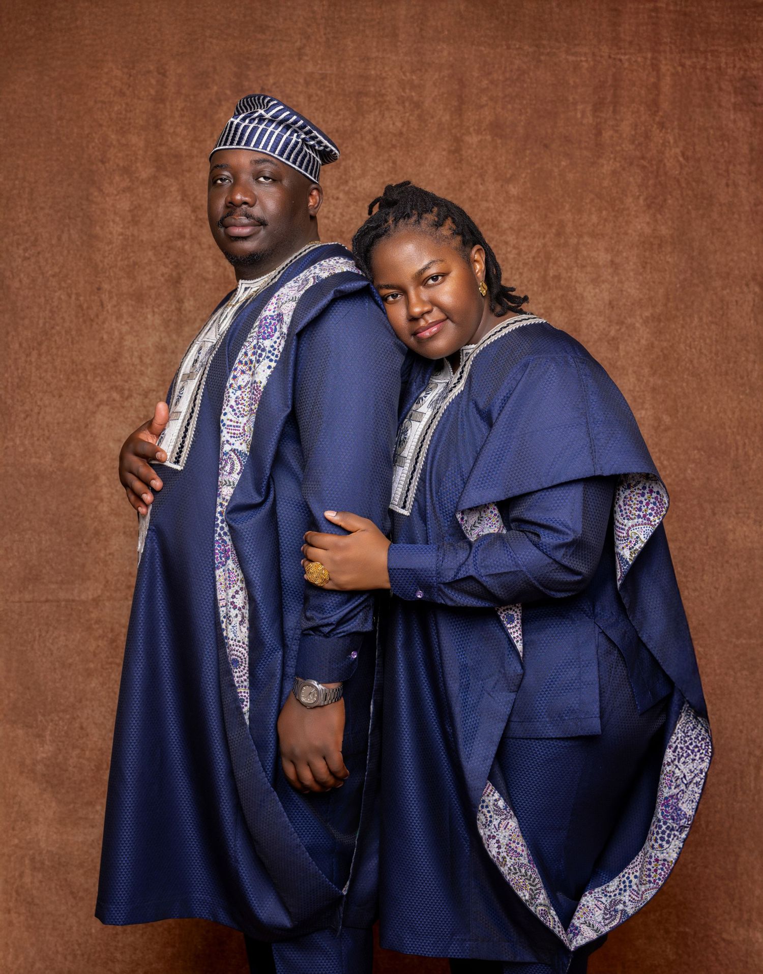Nigerian couple in matching navy blue traditional Yoruba agbada outfits posing together.