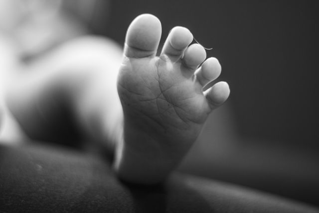 Close-up black and white photo of a newborn baby tiny foot with delicate toes.