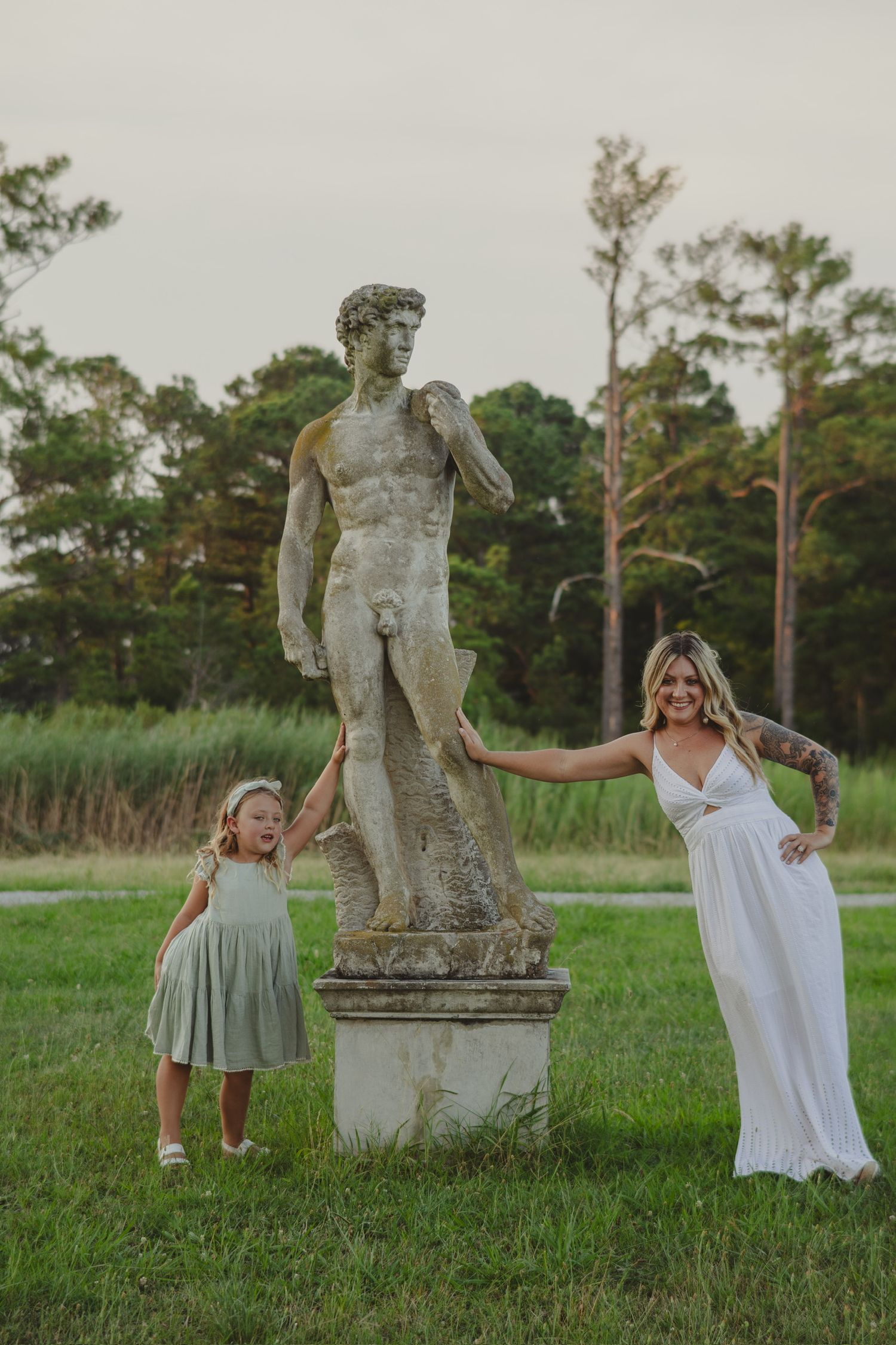woman and daughter leaning an arm on a marble statue of a nude man a captain sinclairs pier