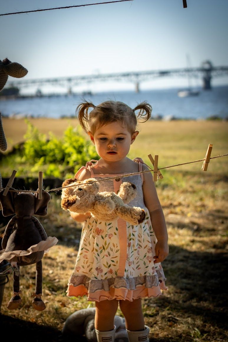 1 and a half year old girl in pigtails hanging stuffed animals out to dry
york river in the background showing the George P coleman bridge