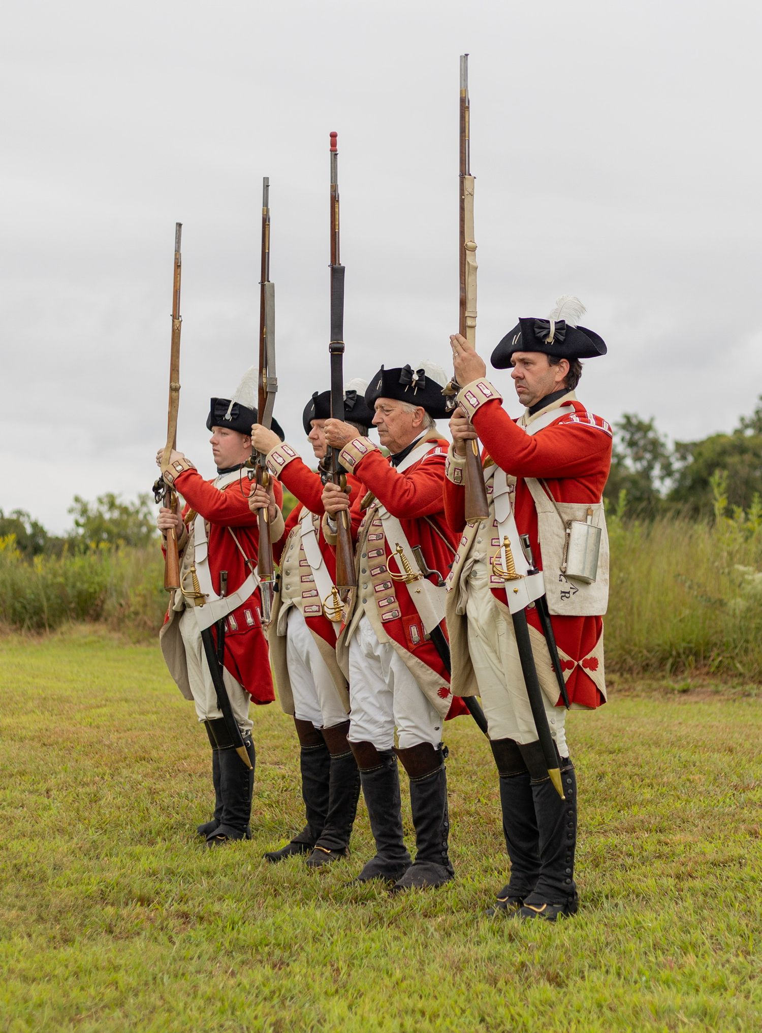 Colonial yorktown reenactment french soldiers wearing red and white uniforms in black boots, holding rifles, while lined up