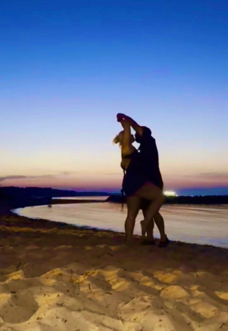 outline of a man and woman dancing on yorktown beach with a pretty sunset