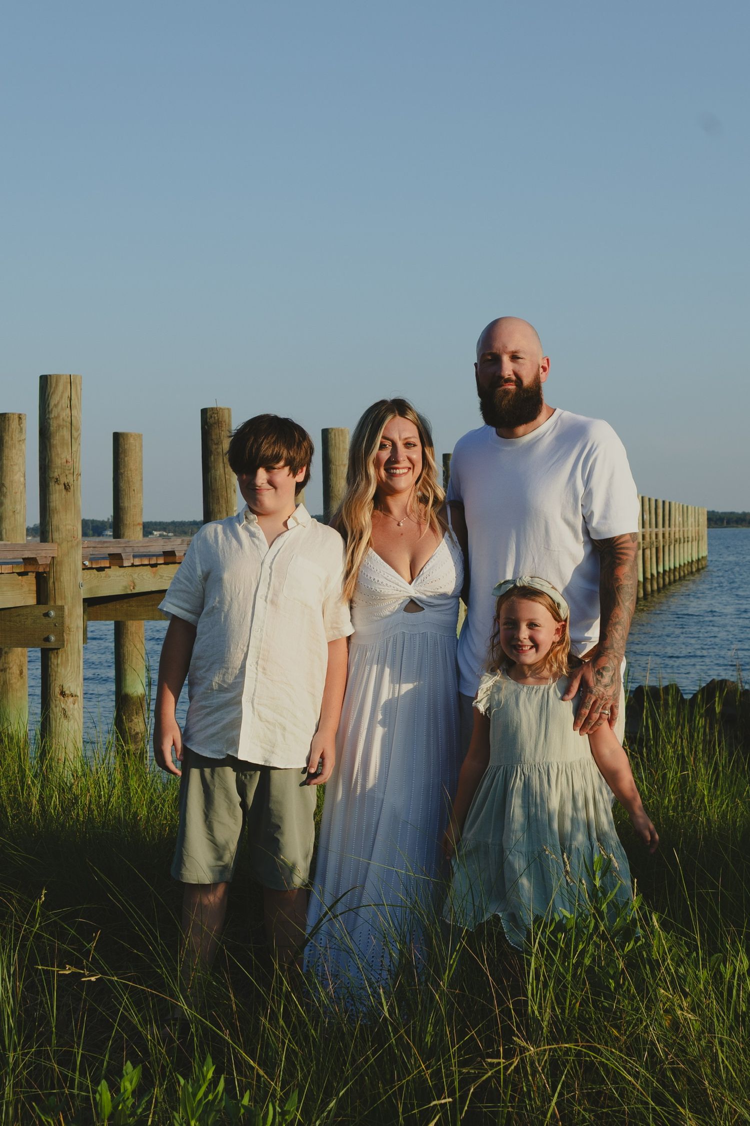 family portrait in creek grass with captain sinclairs pier in the background