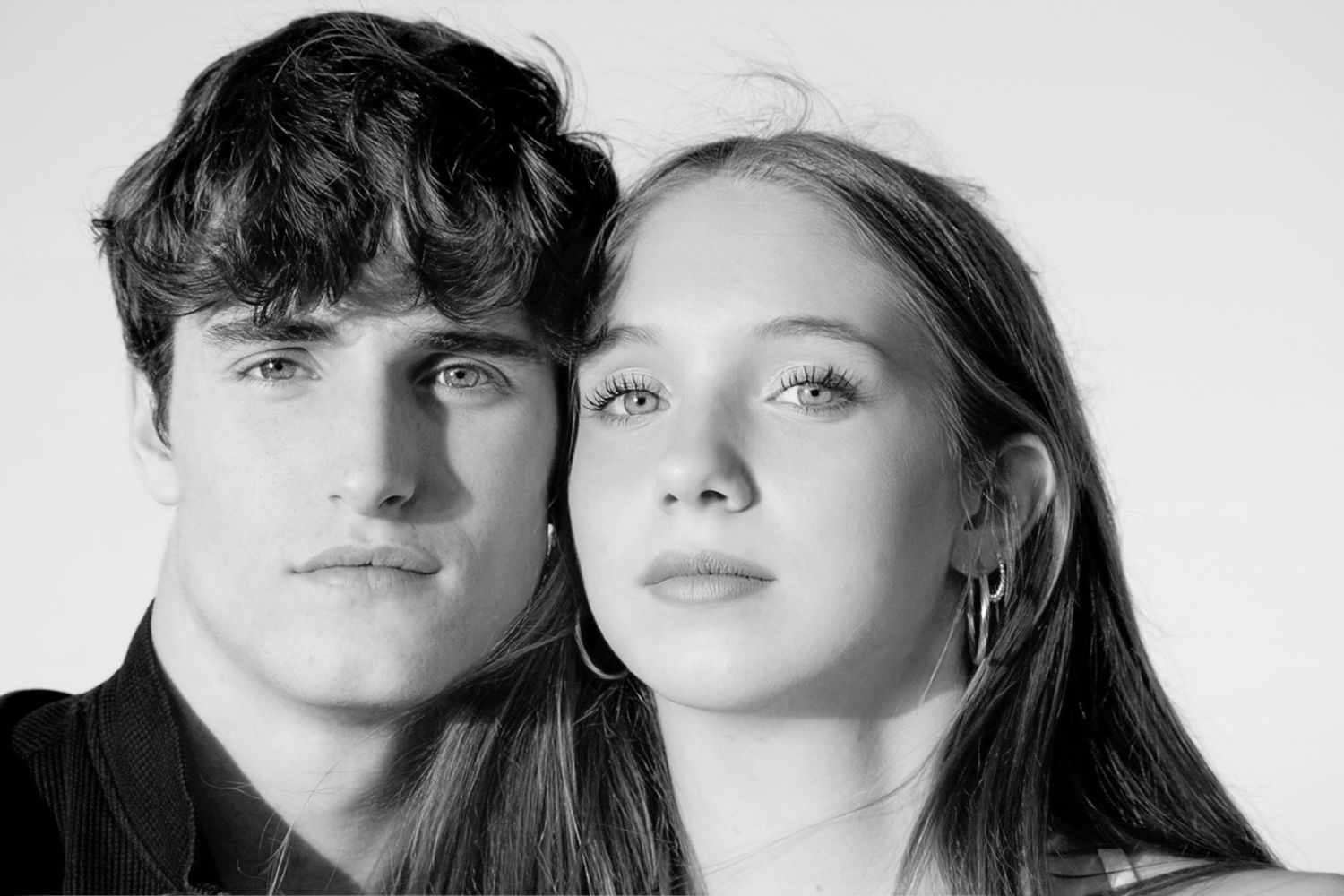Monochrome close-up portrait of a young couple posing together with neutral expressions.
