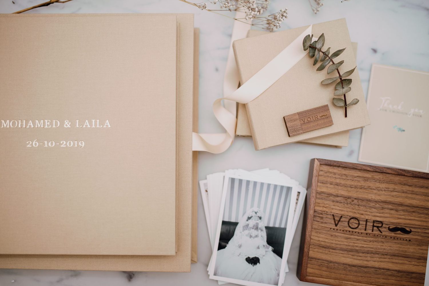 Personalized wedding album set for Mohamed and Laila with photos, USB drive, and keepsake box.