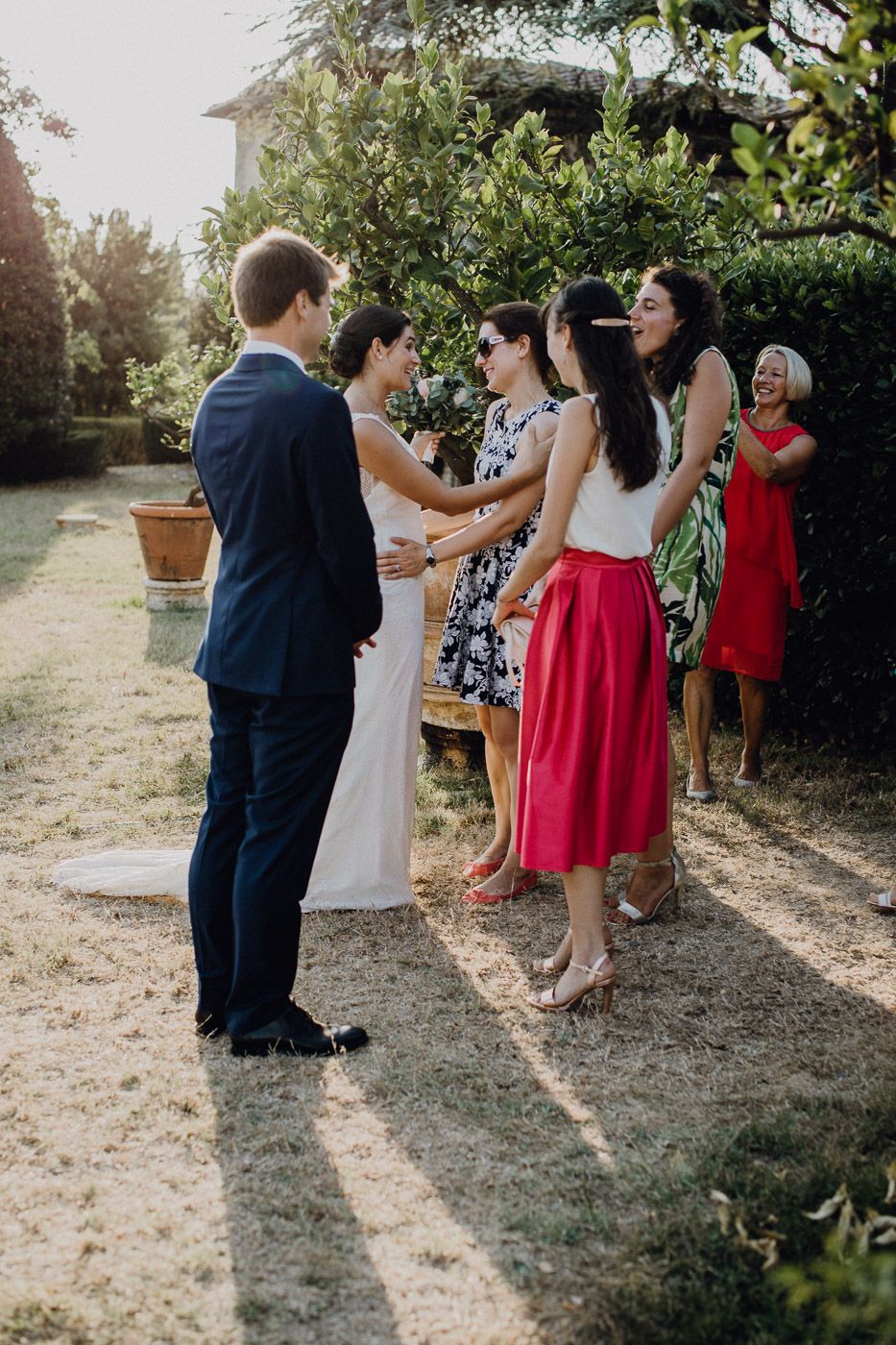 Bride and groom greeting guests in colorful attire at sunny outdoor wedding reception. Tuscany Villa Catignano