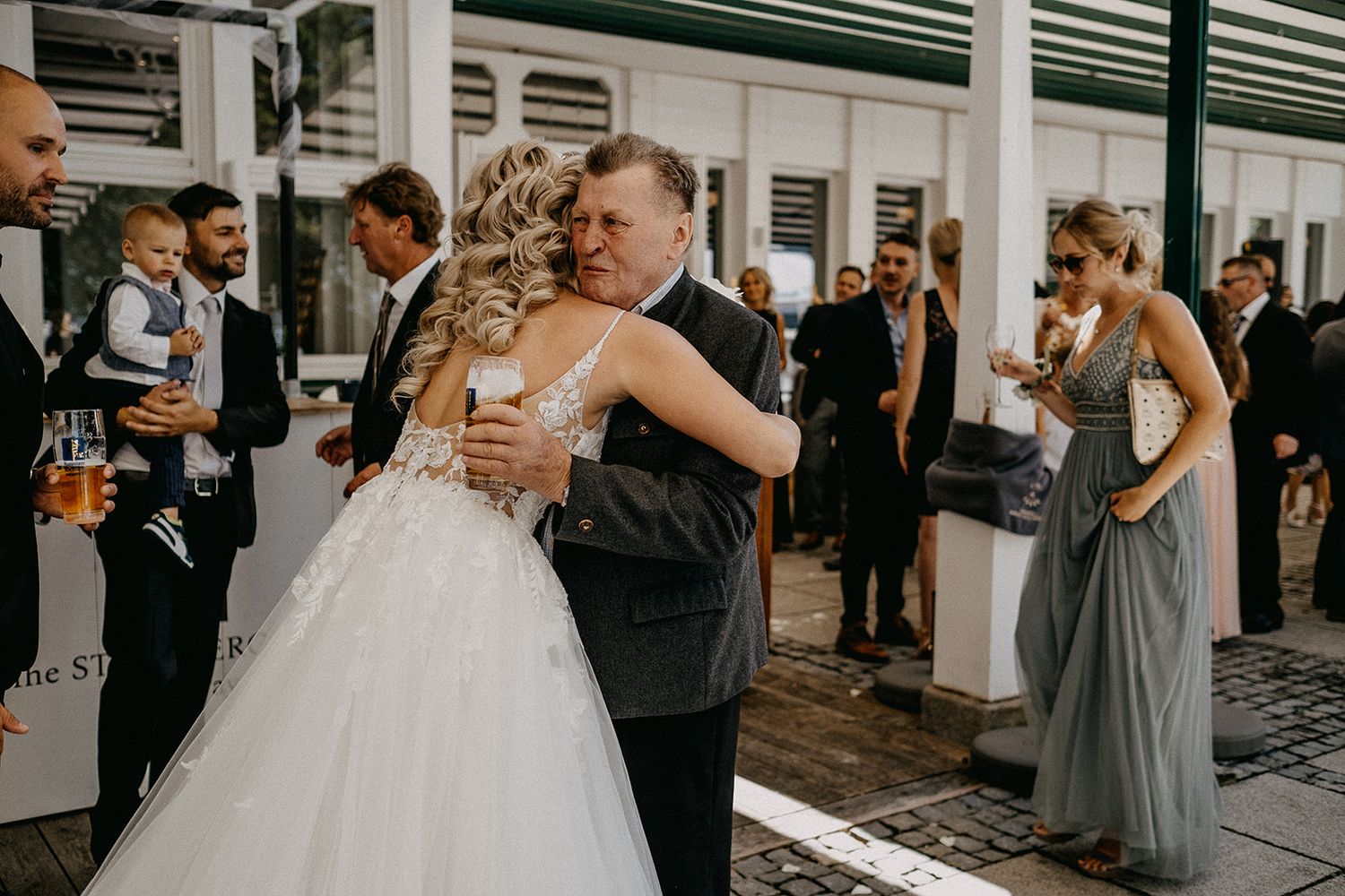 A bride in a ballgown shares a warm embrace with an older gentleman at her wedding reception.