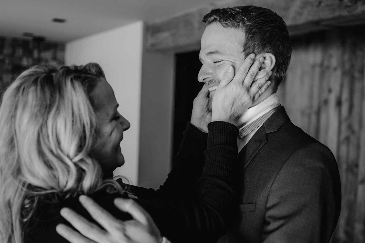Black and white photo of a woman tenderly holding a smiling mans face in a loving moment.