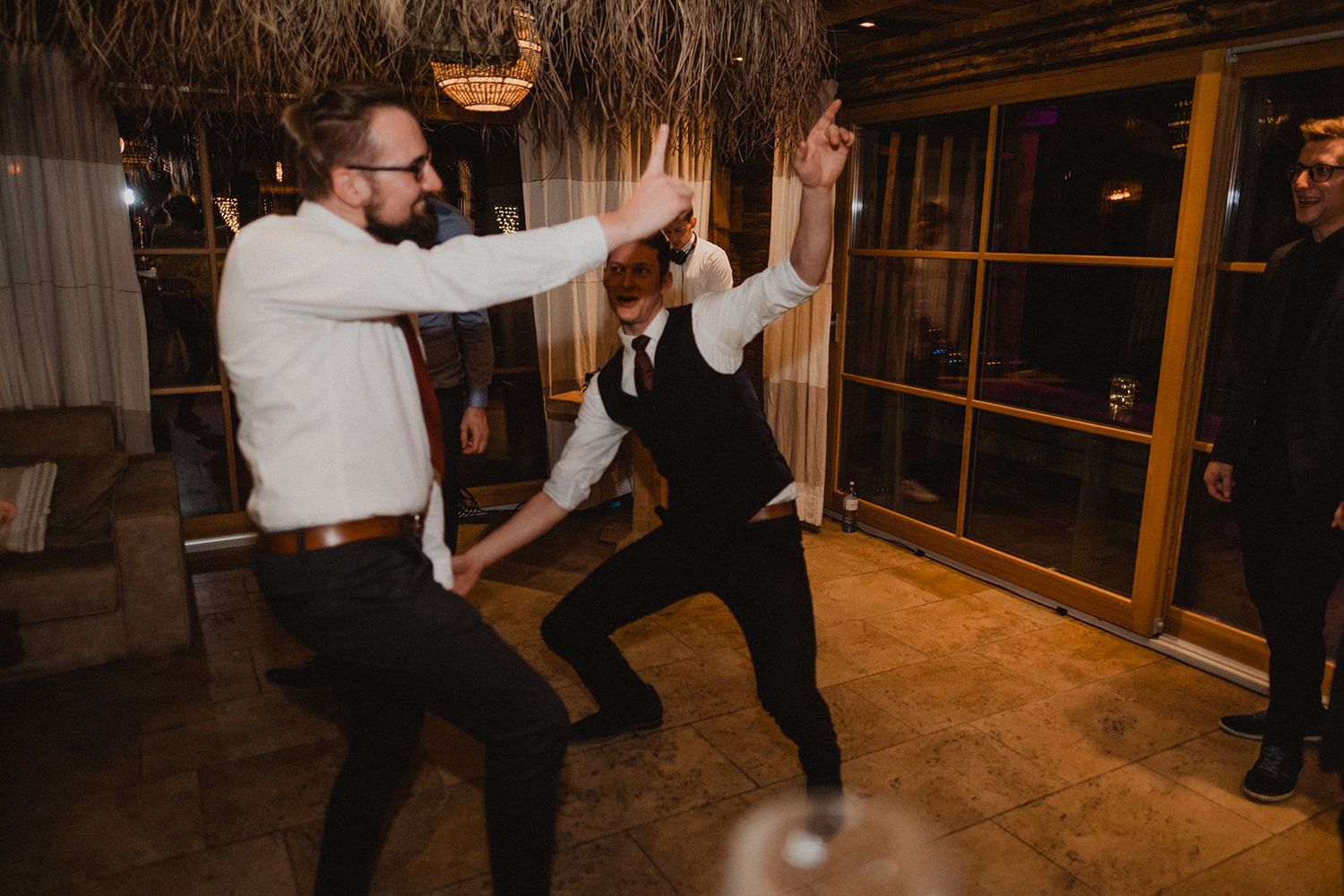 Two men energetically dancing together at a lively wedding reception on the dance floor. Jufenalm