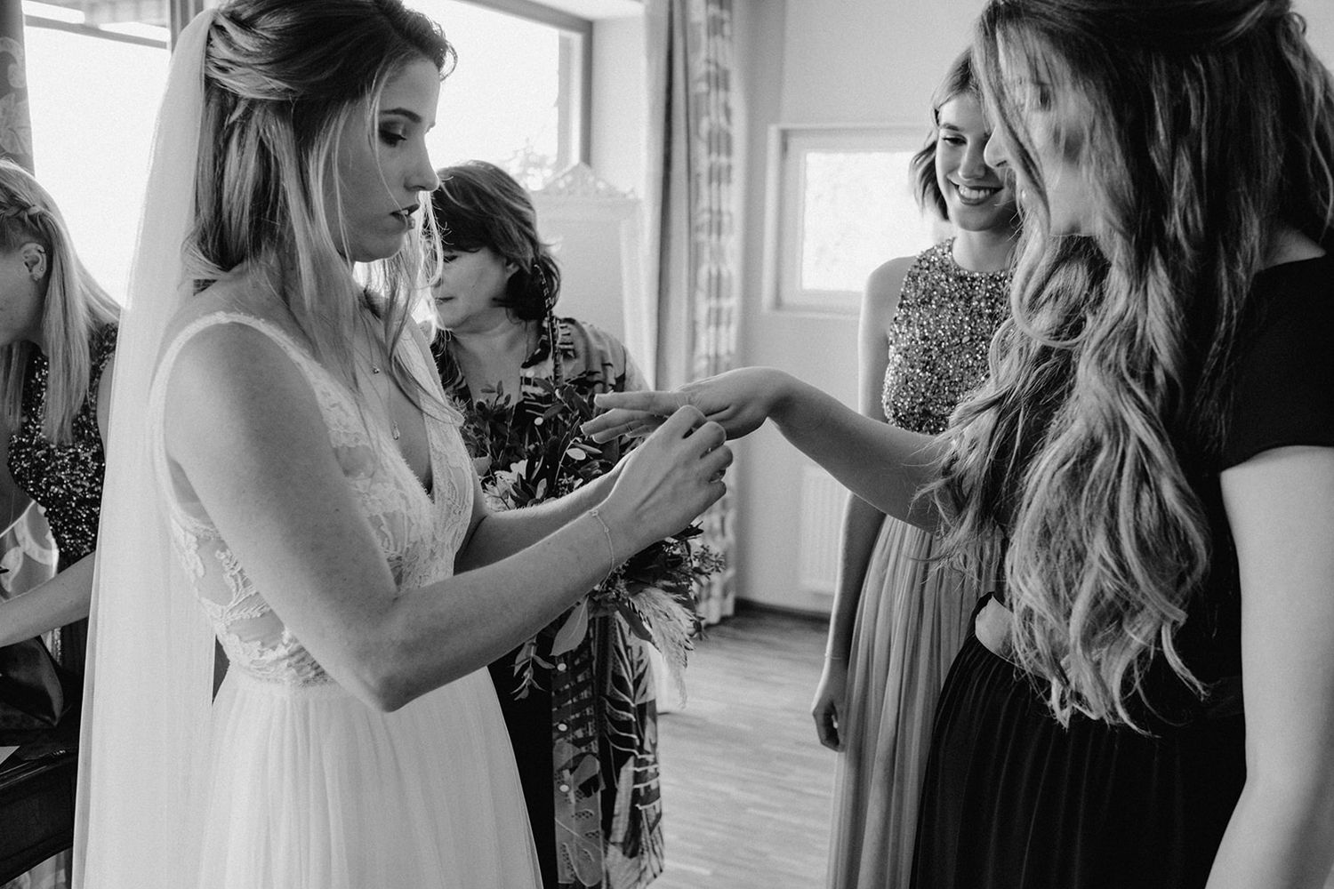 Black and white photo of bride sharing a joyful moment with bridesmaids during wedding preparations.
