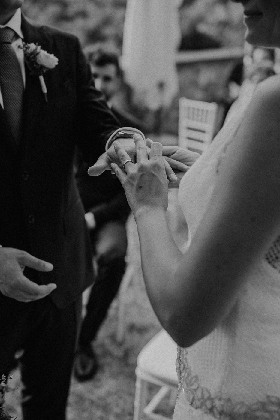 Black and white photo of groom placing wedding ring on brides finger during intimate ceremony exchange. Tuscany Villa Catignano