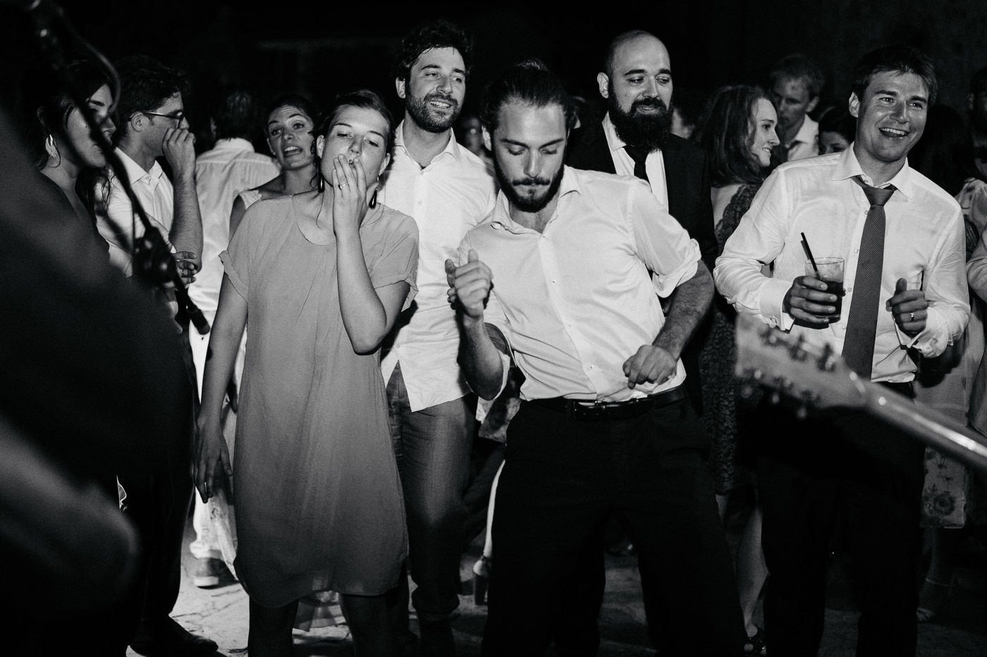 Black and white photo of wedding guests dancing and celebrating joyfully at a lively reception party. Tuscany Villa Catignano