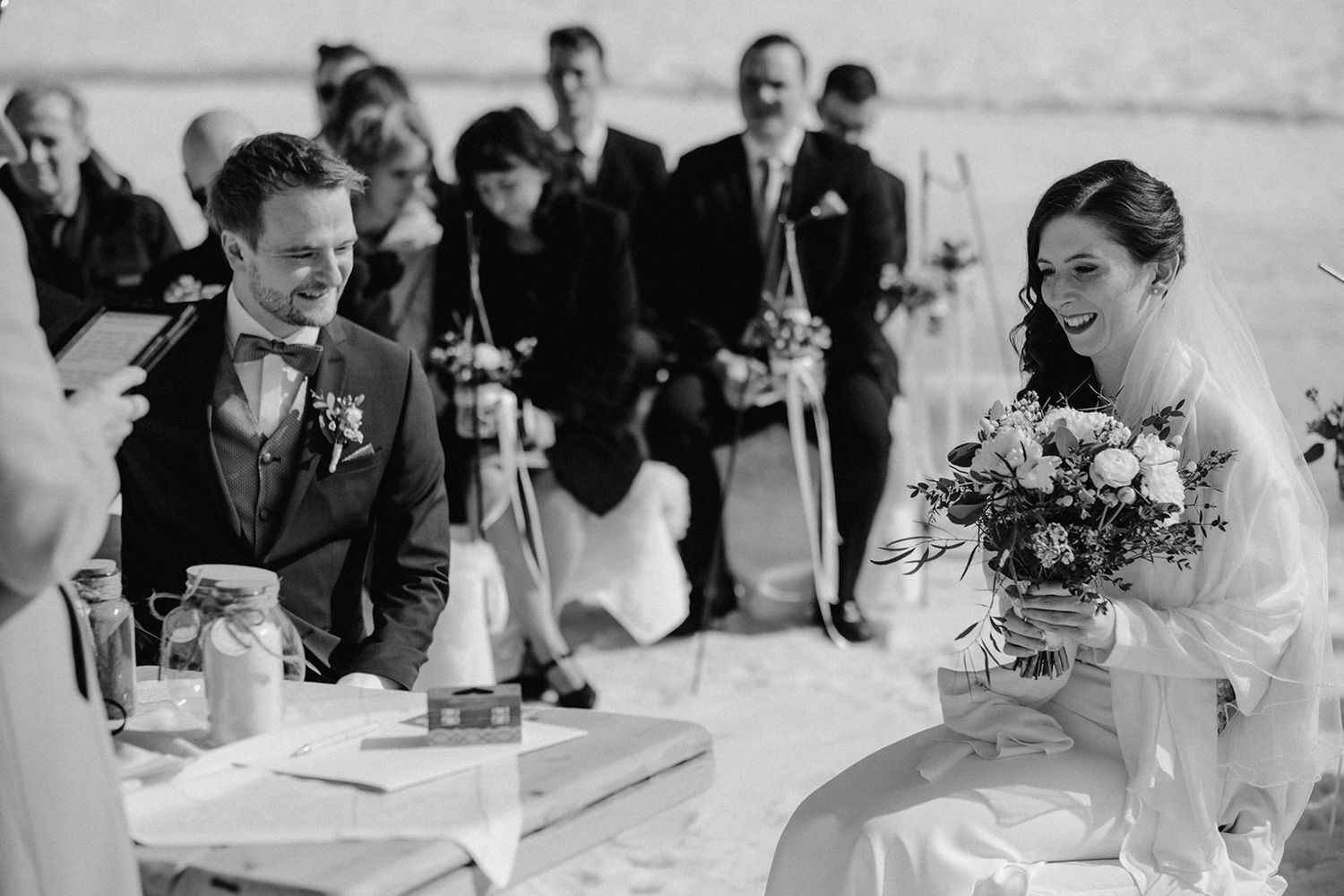 Joyful bride and groom laughing together during outdoor snow wedding ceremony in mountains.