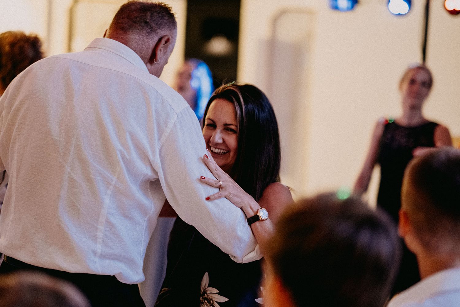Wedding guest couple sharing a warm smile while dancing closely together at the reception party.