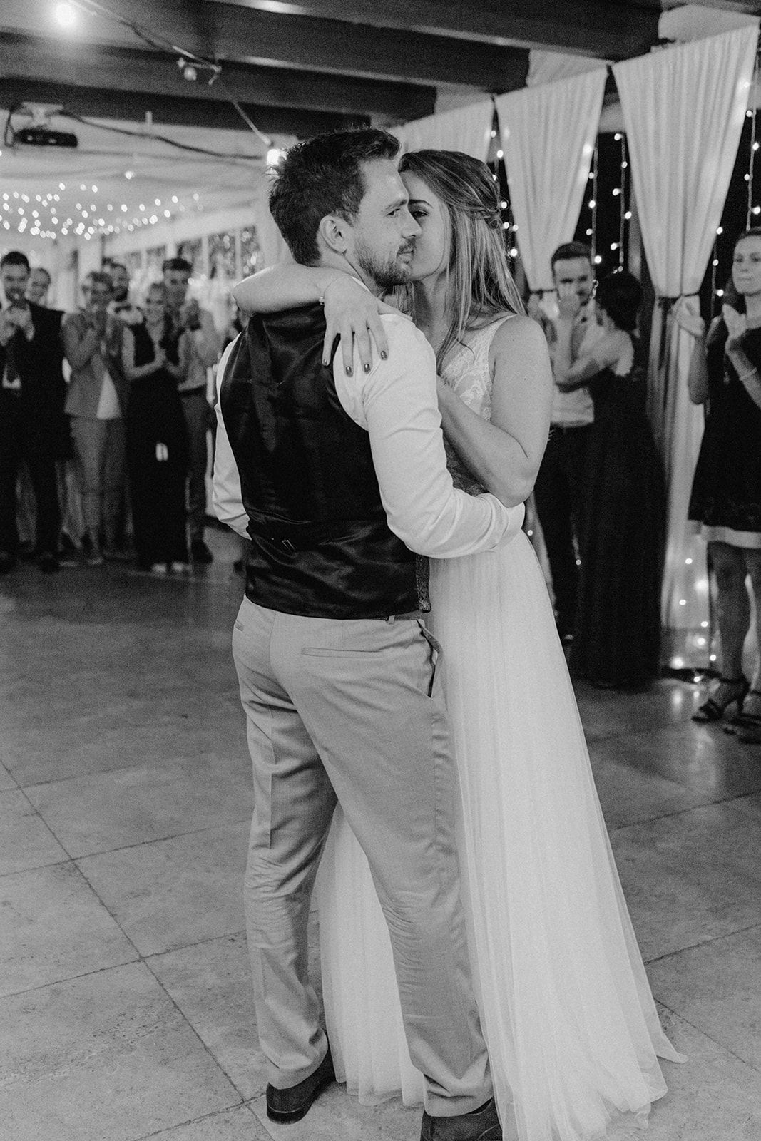 Bride and groom share a romantic kiss during their first dance at the wedding reception.