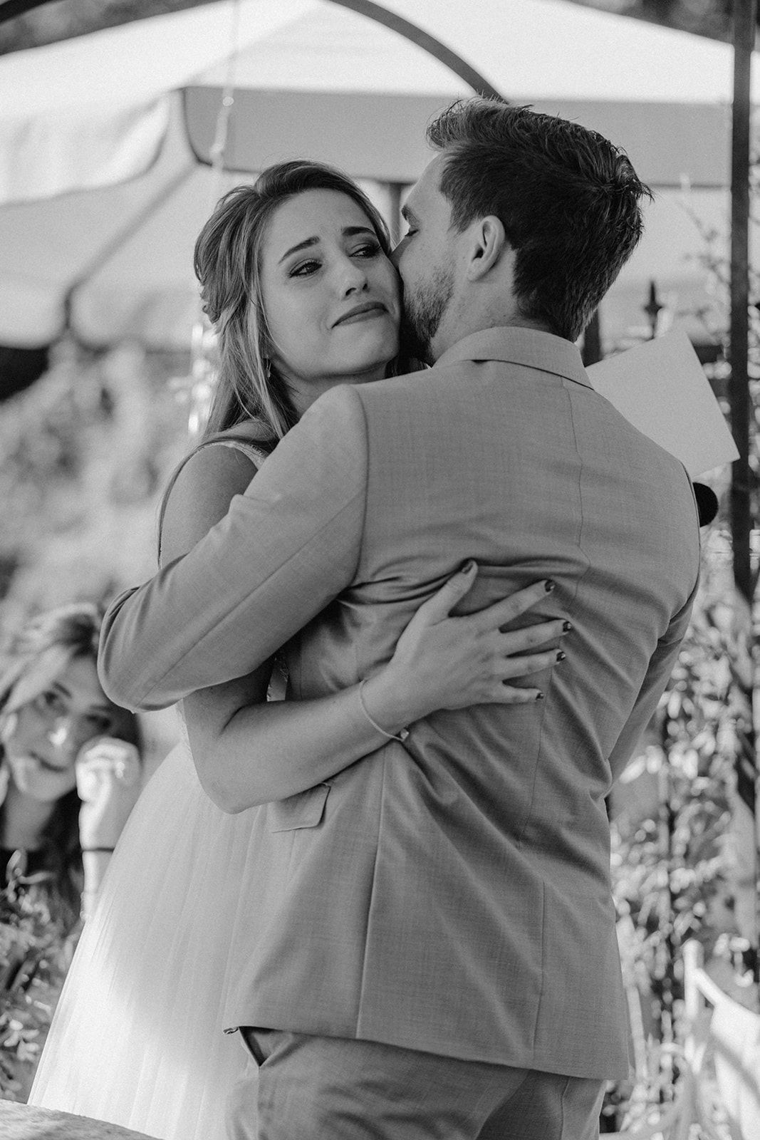 Black and white photo of bride and groom sharing emotional embrace at wedding ceremony.