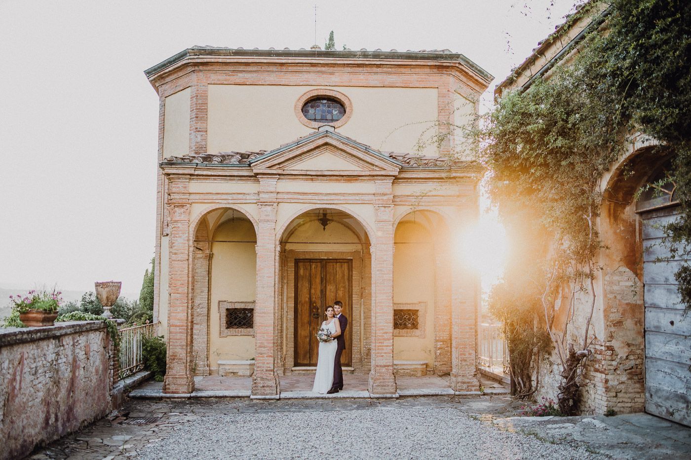 Bride and groom embracing at sunset outside a beautiful Italian villa wedding venue. Tuscany Villa Catignano