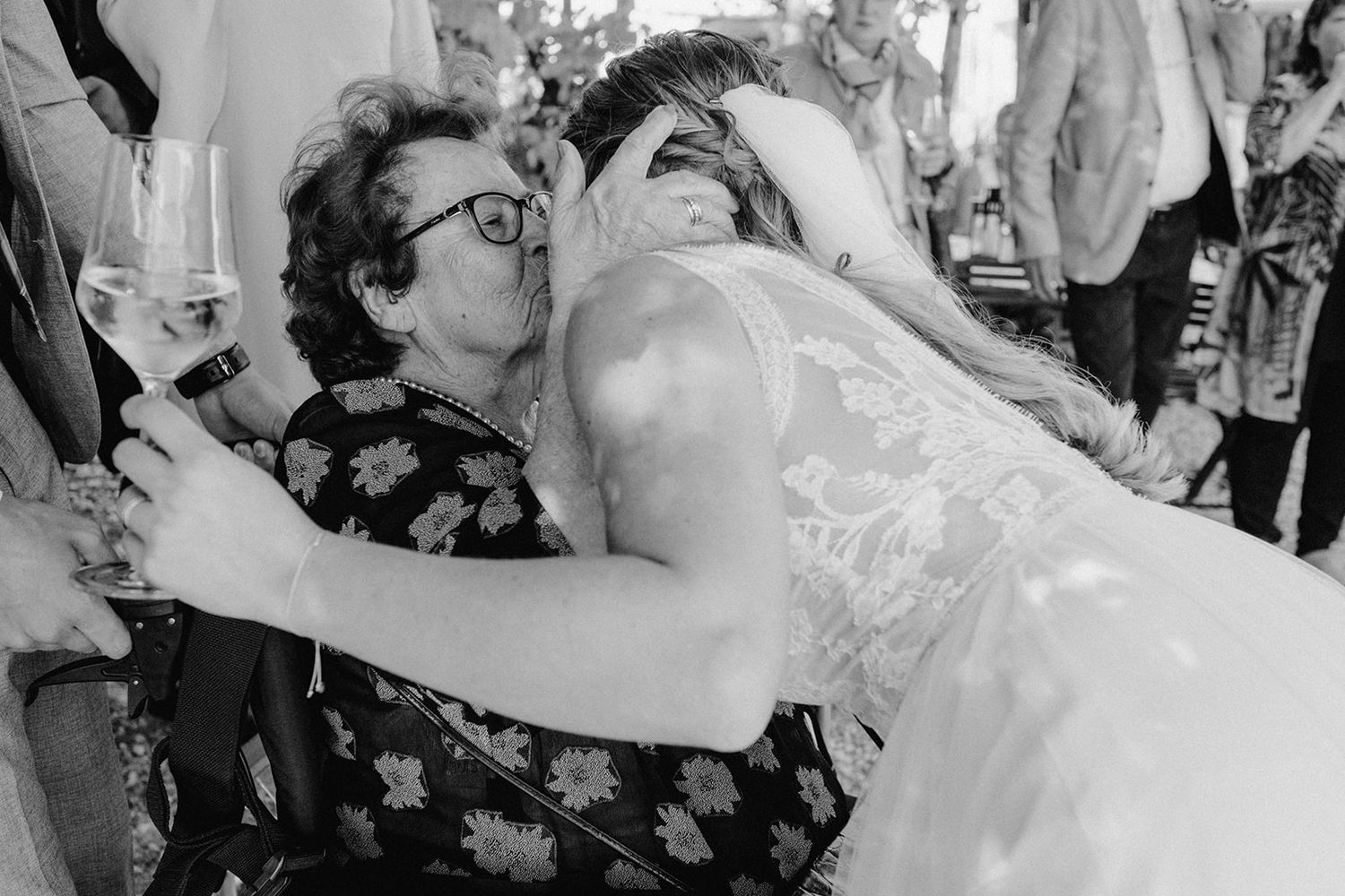 Black and white photo of bride sharing emotional kiss with elderly female wedding guest.