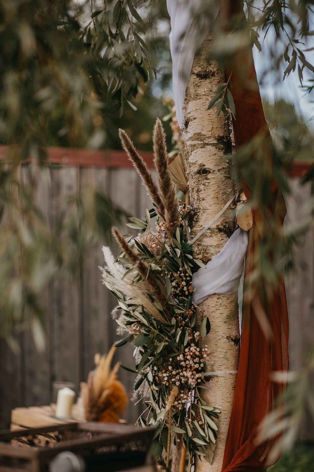 Rustic birch tree wedding arch decorated with pampas grass and dried wildflowers.