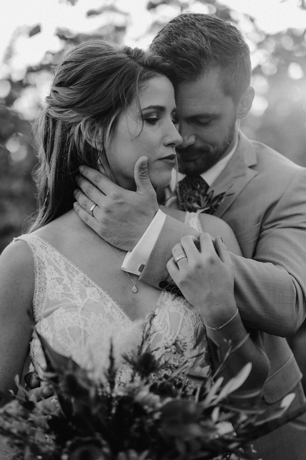 Black and white wedding portrait of bride and groom embracing tenderly, groom holding bride's face gently.