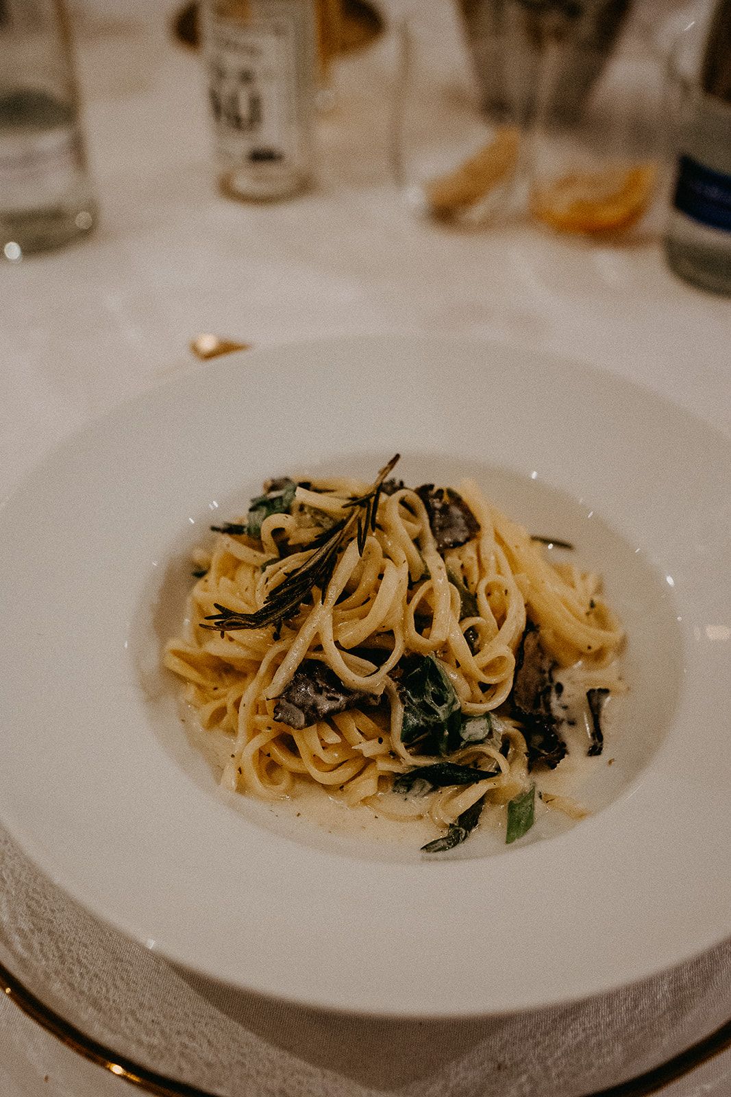 Elegant pasta dish with herbs and mushrooms served on a white plate at a wedding reception dinner.