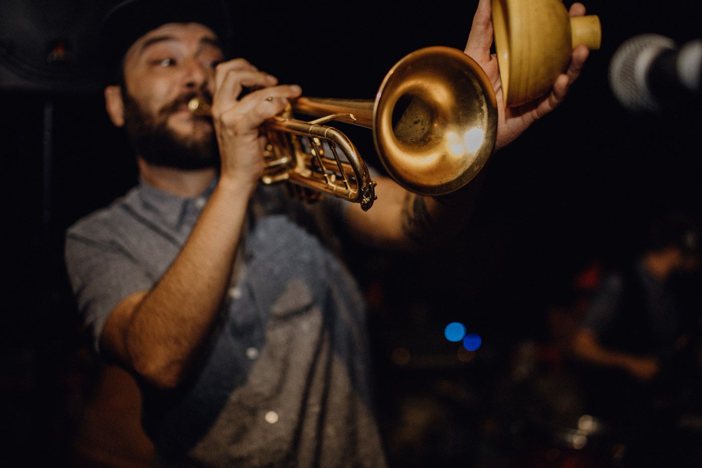 Bearded musician playing brass trumpet at live music performance in dimly lit venue. Tuscany Villa Catignano