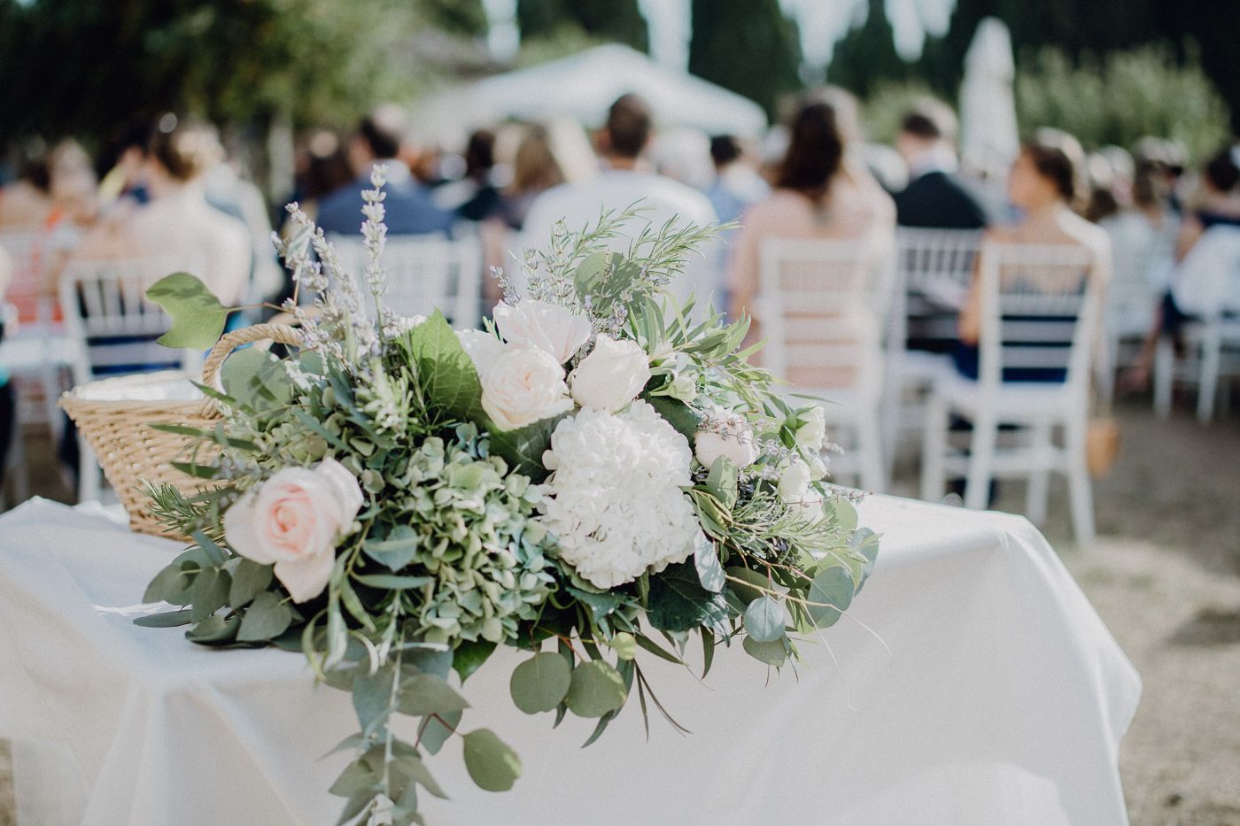 Elegant white and green floral centerpiece with roses and eucalyptus at outdoor wedding ceremony. Tuscany Villa Catignano