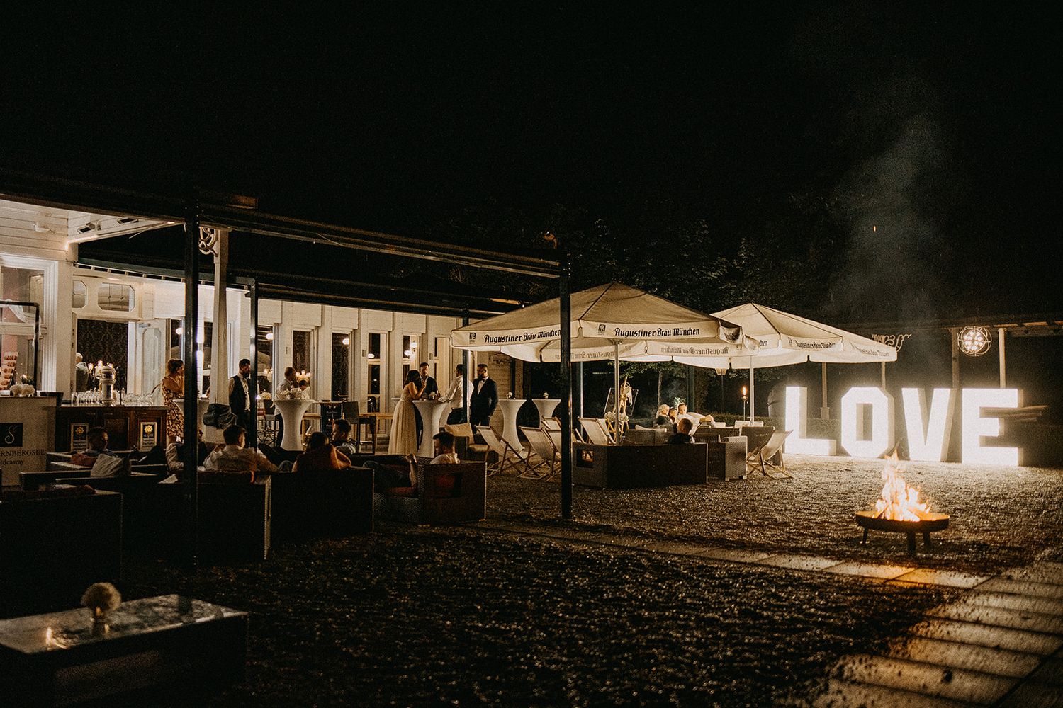 Outdoor wedding venue at night featuring illuminated LOVE sign and bonfire ambiance.